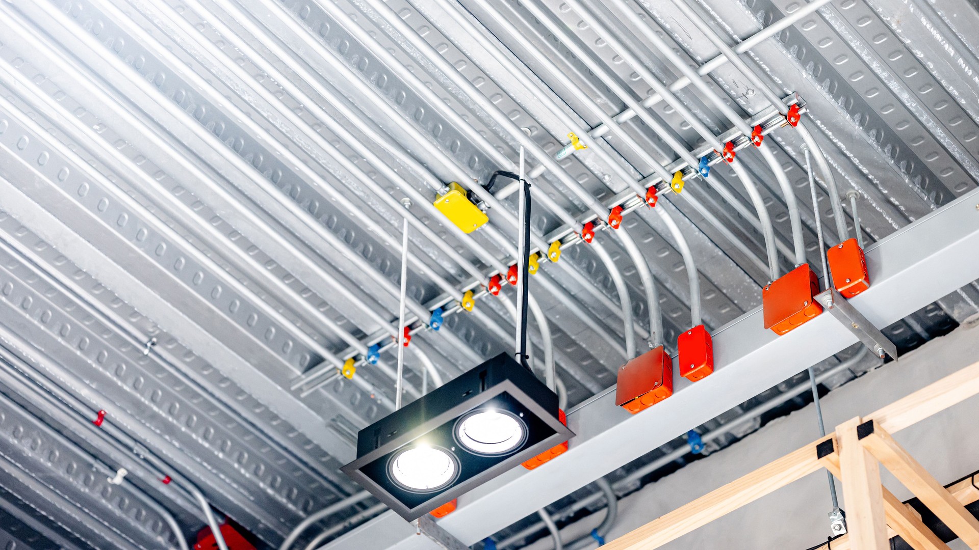 Electrical cable conduit with colorful junction box for the electric wiring system with spotlight lamp on metallic ceiling in modern building. Pipe and fitting equipment for power and lighting system